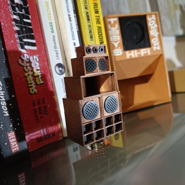 Spring-mounted mini reggae sound system replica positioned among music-themed books.